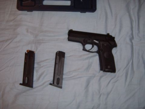 1988 Ford Bronco - A pistol and two magazines are laid out on a white cloth next to a black carrying case.