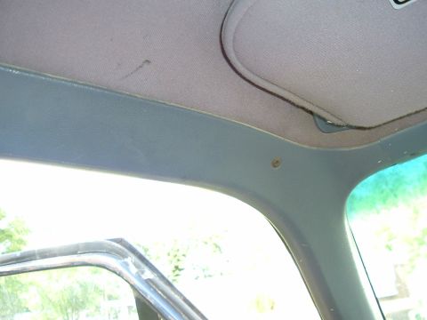 1989 Ford Bronco - Interior view of a car's headliner, sun visor, and A-pillar with blue trim.