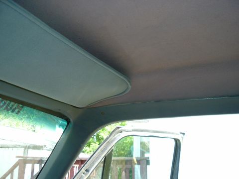 1989 Ford Bronco - The photo shows the interior headliner and sun visor of a vehicle, with a glimpse of the outside through the window.