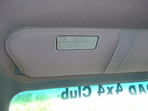 1989 Ford Bronco - Close-up of a vehicle's sun visor showing a caution label with text about vehicle use.