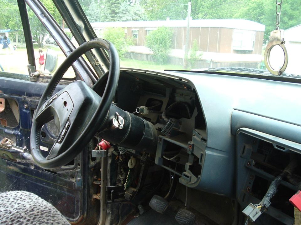 1989 Ford Bronco interior showing disassembled dashboard, steering wheel, and pedals