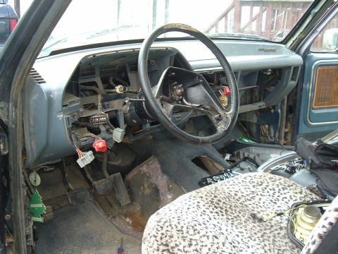1989 Ford Bronco - The interior of a vehicle shows significant disassembly, with wiring and dashboard parts exposed.