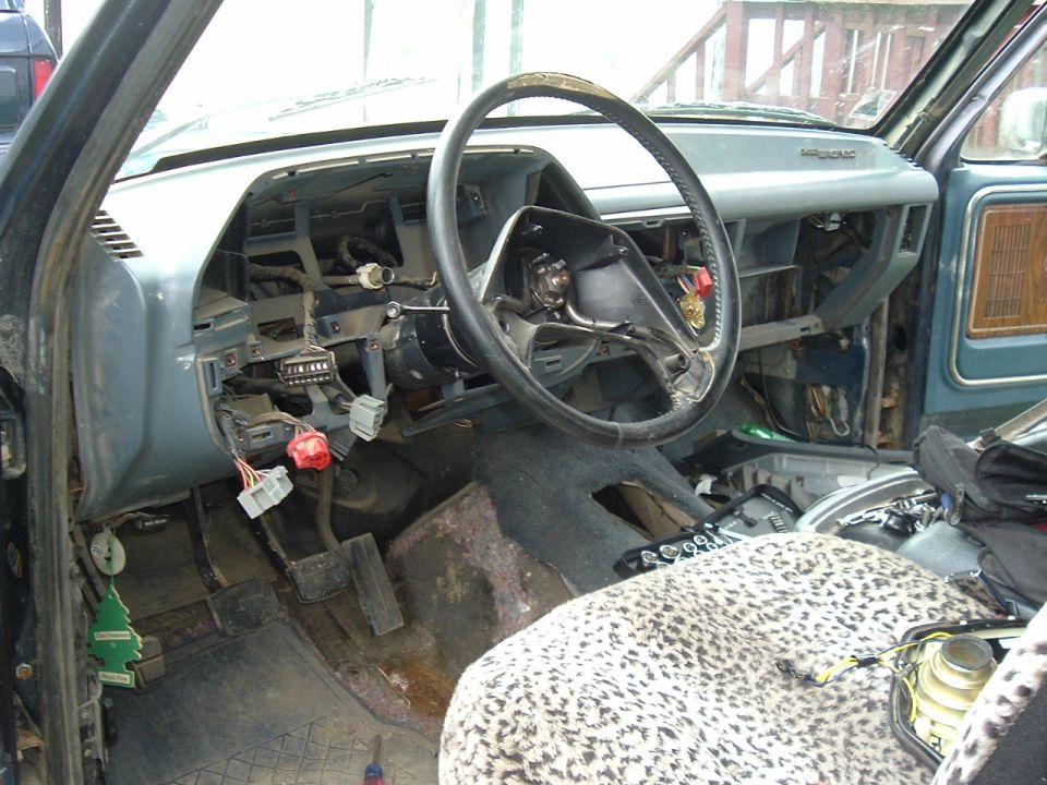 Interior of a disassembled vehicle with exposed wiring and dashboard components