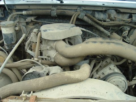 1989 Ford Bronco - Engine bay components covered in dust. Visible text includes 'CAUTION' on the fan shroud.