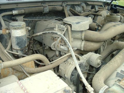 1989 Ford Bronco - A dusty engine bay with various hoses and mechanical parts visible.