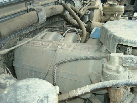 1989 Ford Bronco - Close-up view of a dirty engine compartment, showing various hoses and mechanical parts.