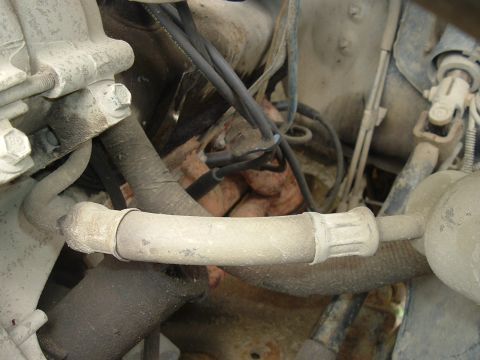 1989 Ford Bronco - Close-up view of engine components, including hoses and wiring, within a vehicle's engine compartment.