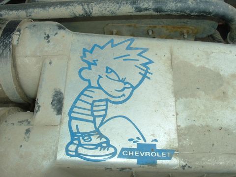 1989 Ford Bronco - A sticker of Calvin peeing on a Chevrolet logo is affixed to a dirty engine component.