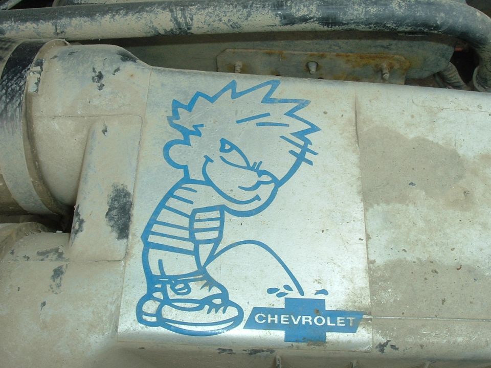 Engine component with blue Calvin sticker and Chevrolet logo. Dusty and stained