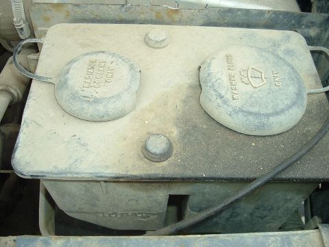 1989 Ford Bronco - Engine bay component with caps for washer fluid and coolant. Year unknown.