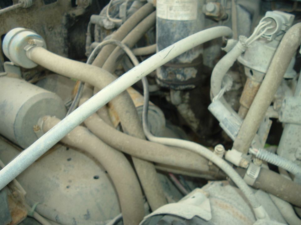 Engine compartment with numerous hoses and wires, some dusty and worn