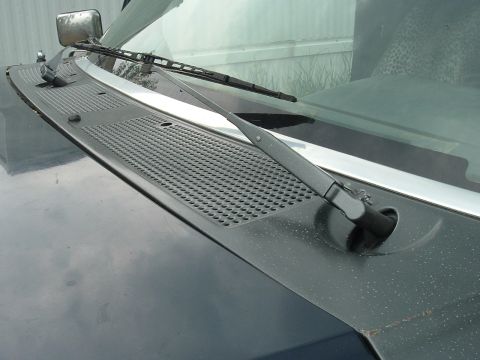 1989 Ford Bronco - Close-up view of the windshield wiper assembly and cowl vent on a dark colored vehicle.