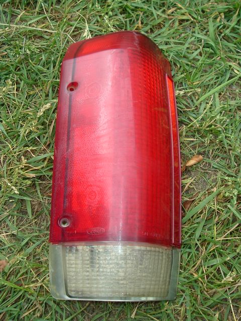 1989 Ford Bronco - A single taillight assembly, likely for a Ford Bronco, rests on grass.