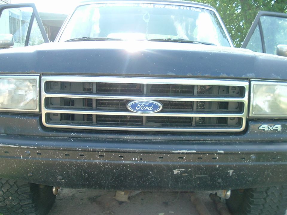 Front of a dark-colored Ford truck with doors open. Grille has a Ford logo. 4x4 badge visible on the right