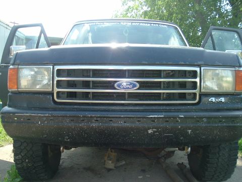 1989 Ford Bronco - Front view of a black Ford truck with its doors open, showing the grille and 4x4 badging.