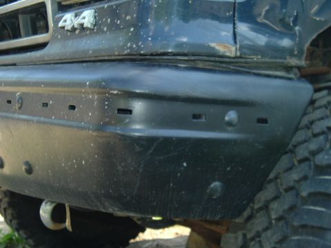 1989 Ford Bronco - The front corner of a dirty SUV shows a '4x4' badge and part of the grille.