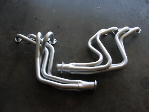 1979 Ford Bronco - A pair of silver exhaust headers are displayed on a dark, textured surface.