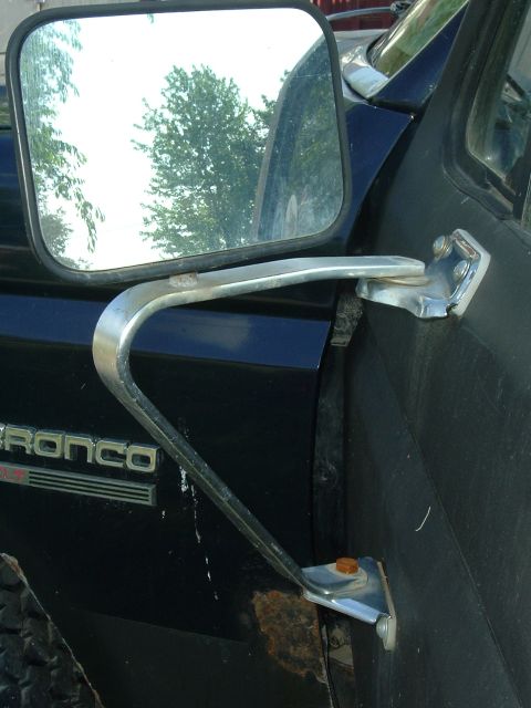 1989 Ford Bronco - Close-up of the side mirror assembly on a 1989 Ford Bronco, showing the door panel and badging.
