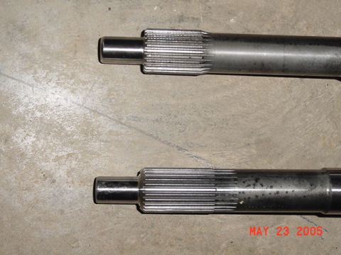 2003 Ford Mustang - Two metal shafts with splined ends are shown on a concrete surface.
