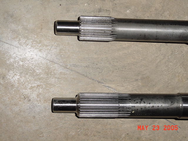 Two metal shafts with splined ends on a concrete surface. Watermark reads 'MAY 23 2005 SUPERMOTORS www.supermotors.net'