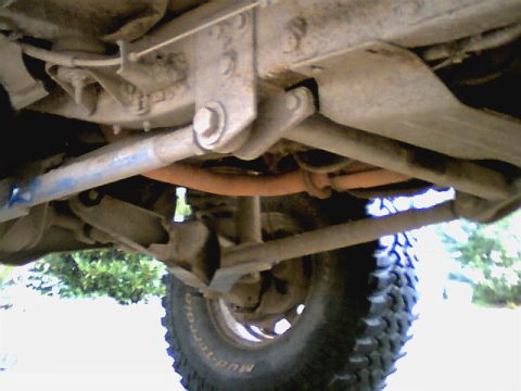 1987 Ford Bronco II - The undercarriage of a modified vehicle is shown, with a focus on its suspension components and exhaust pipe.