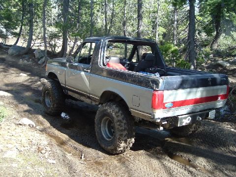 1989 Ford Bronco - This lifted Ford Bronco navigates a muddy path through a wooded area.