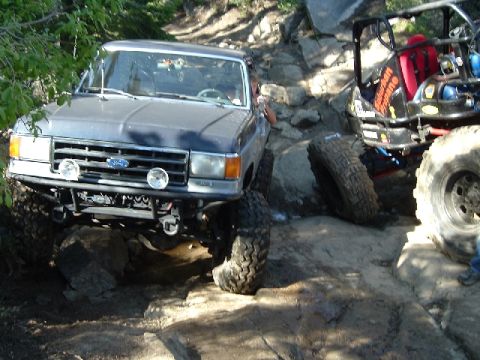1989 Ford Bronco - A modified Ford Bronco tackles a challenging off-road trail alongside another vehicle.