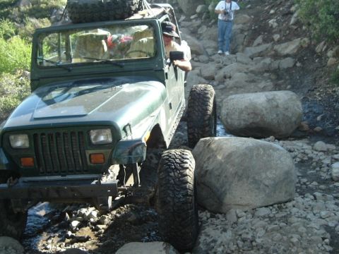 1989 Ford Bronco - A Jeep Wrangler carefully maneuvers over large rocks on a challenging off-road trail.