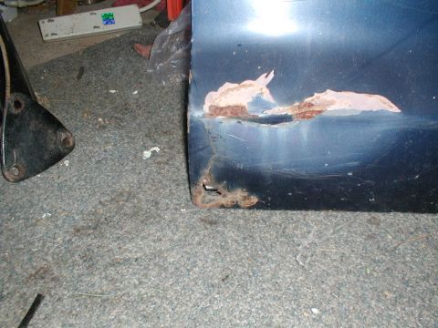 1979 Ford Bronco - Close-up of a damaged blue car door panel showing extensive rust.
