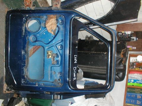 1979 Ford Bronco - Disassembled blue car door with "LEFT DRIVER" handwritten on the interior frame.