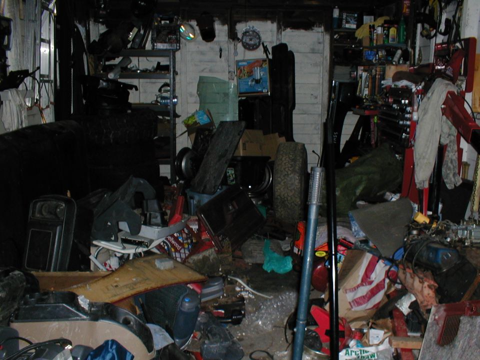 Cluttered garage interior with shelves, tires, and tools