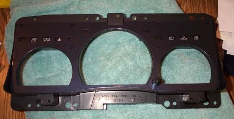 1998 Ford Crown Victoria - This is a vehicle's gauge cluster bezel, showing indicator light cutouts and part numbers stamped on the back.