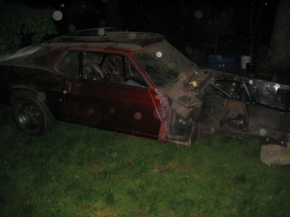 car body with no front end, missing doors, and roll cage visible inside