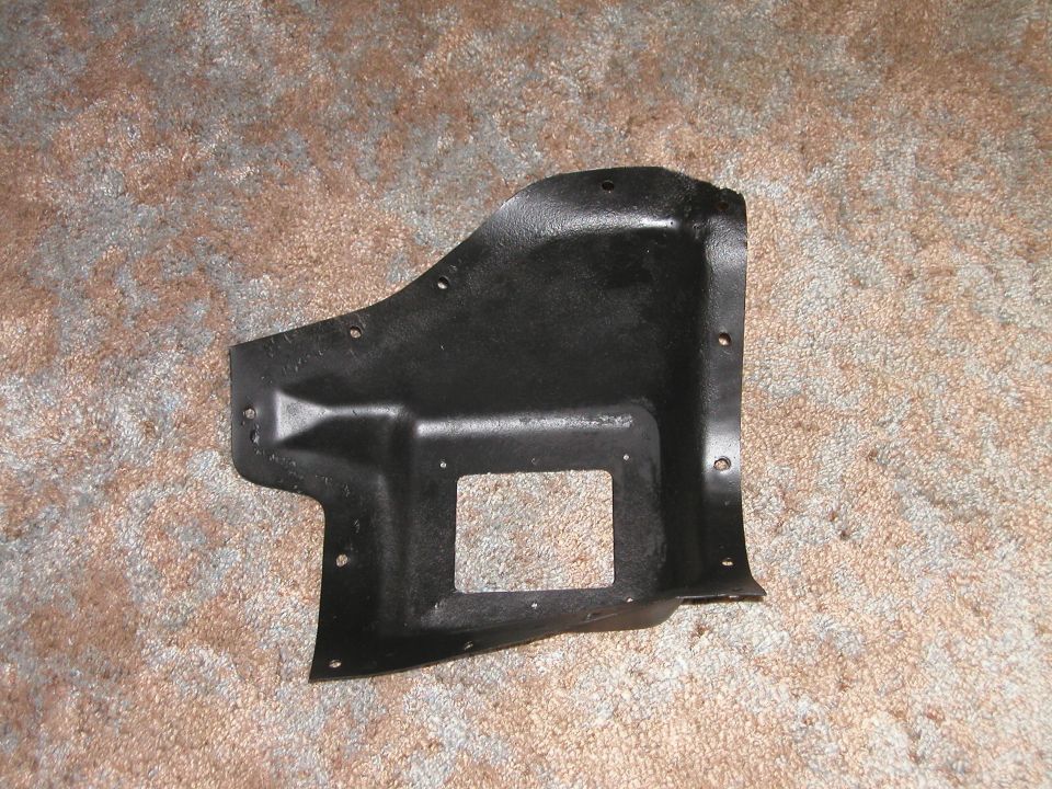 Black metal automotive panel with rectangular cutout and mounting holes on carpet