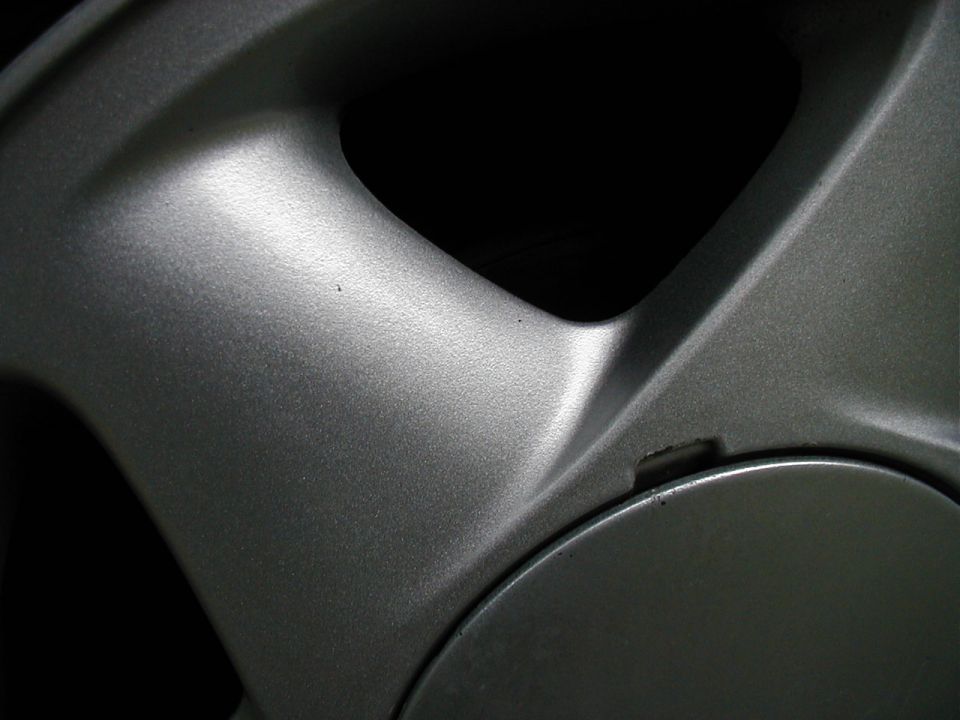 Close-up of a silver car wheel rim with a dark center