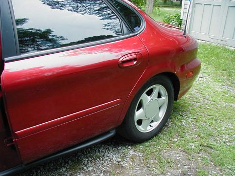 1997 Ford Taurus - Rear passenger side of a red 1997 Ford Taurus sedan parked on gravel and grass.