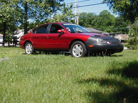 1997 Ford Taurus - Red 1997 Ford Taurus sedan with a car bra parked in a grassy area.