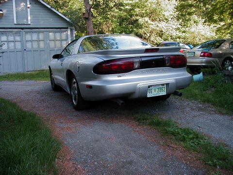 1997 Ford Taurus - Rear view of a silver Pontiac Firebird parked in a driveway next to a garage.