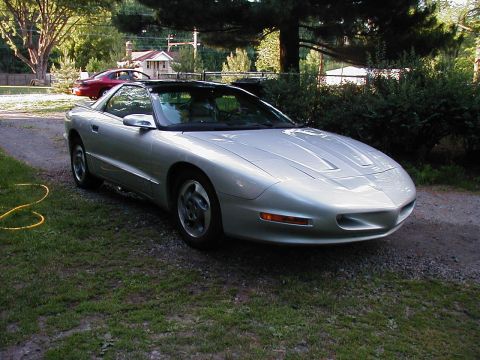 1997 Ford Taurus - A silver 1997 Pontiac Firebird is parked on a gravel driveway, with a red car in the background.