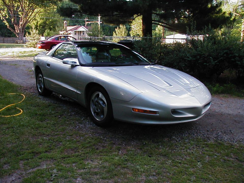 Silver 1997 Pontiac Firebird, 3q-front view. Another red car is visible in the background