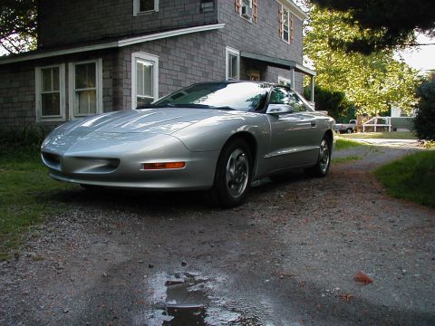 1997 Ford Taurus - A silver Pontiac Firebird is parked on a gravel driveway in front of a gray house.