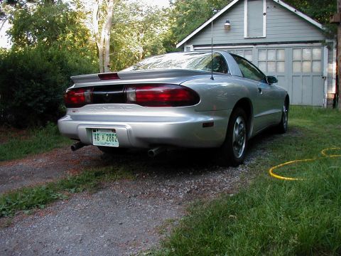 1997 Ford Taurus - Rear view of a silver Pontiac Firebird parked in a gravel driveway next to a garage.