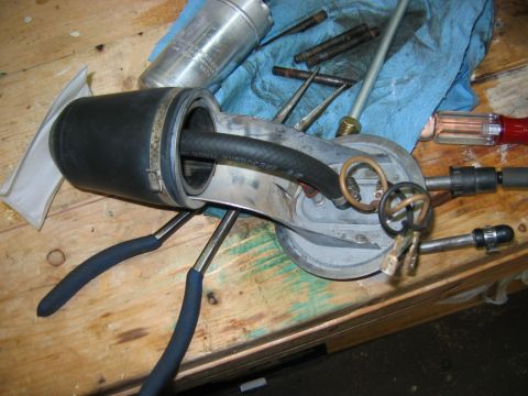1985 Ford Crown Victoria LTD - A disassembled fuel pump assembly, including a hose and pliers, rests on a wooden workbench.