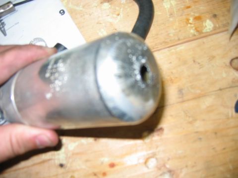 1985 Ford Crown Victoria LTD - A fuel pump is held in a hand over a wooden workbench, with a black hose attached.