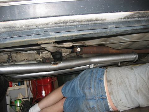 1985 Ford Crown Victoria LTD - A person works on the exhaust system and driveshaft underneath a vehicle.