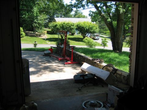 1985 Ford Crown Victoria LTD - A white van is visible parked in a driveway, viewed from inside a garage with an engine hoist and other items in the foreground.