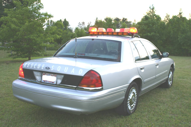 Silver sedan with 'RESCUE SQUAD' on trunk and a light bar on the roof