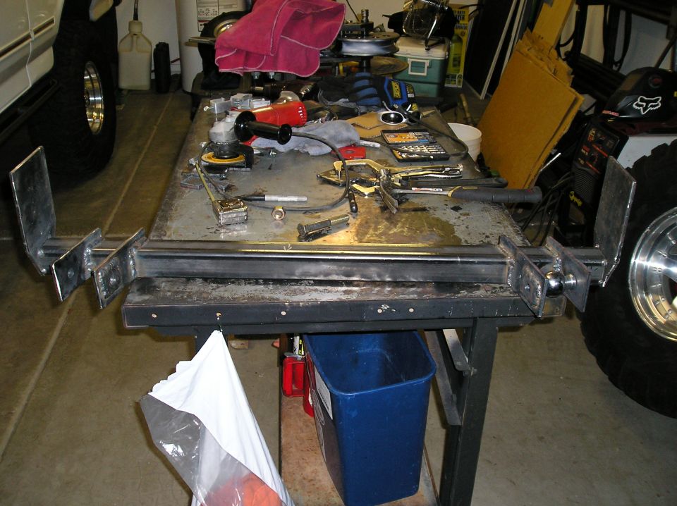Home-built steel bumper with hitch ball on garage welding table beside tools