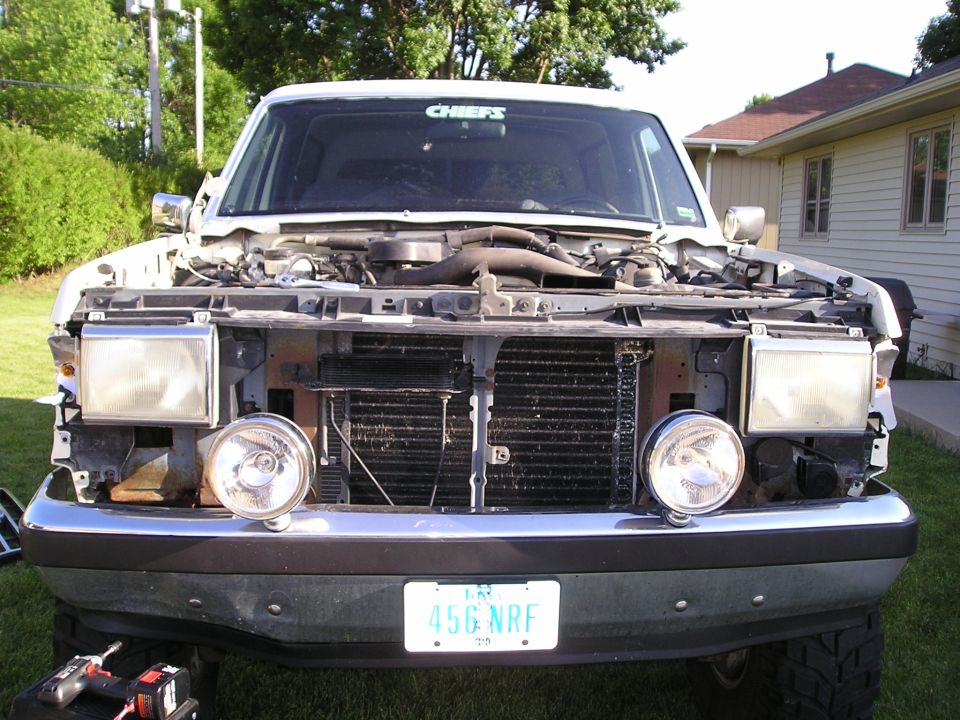 White Ford Bronco front view with grille removed, exposing radiator; round driving lights on bumper, plate 456 NRF