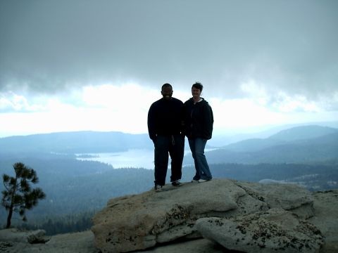 1989 Ford Bronco - A scenic view of a lake and mountains from a high vantage point, with two individuals observing the landscape.